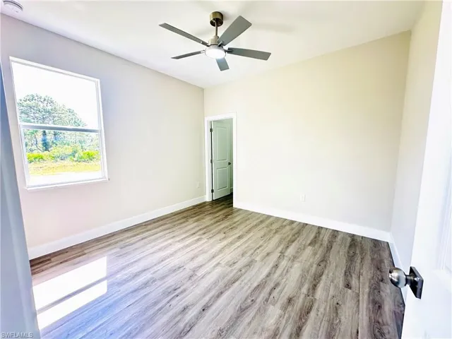Spare room featuring wood finished floors, a smoke detector, and a ceiling fan