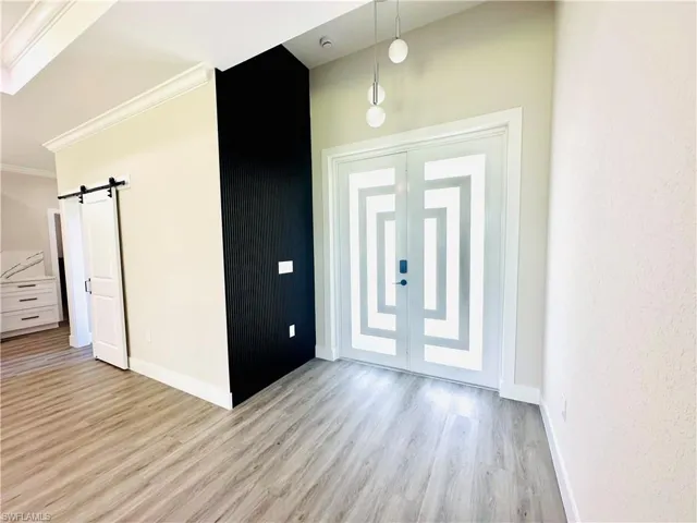 Entryway with a barn door, light wood-type flooring, and crown molding