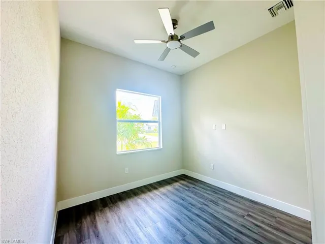 Den - Unfurnished room with dark wood-type flooring and ceiling fan