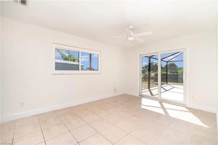 Spare room with light tile patterned floors, a sunroom, and a ceiling fan