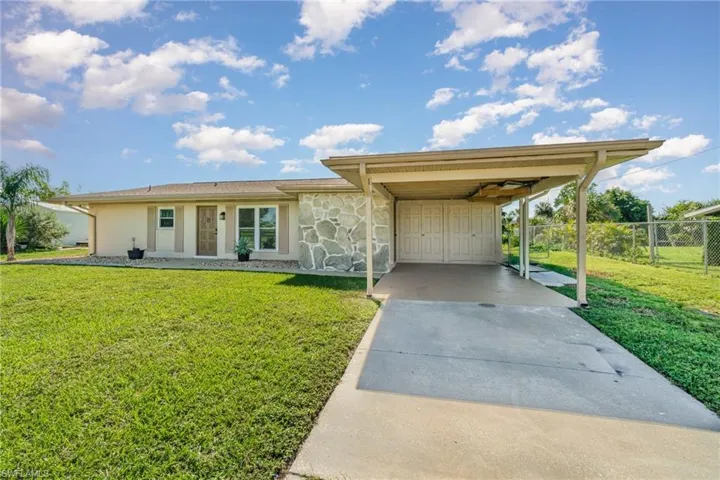 View of front facade with a carport, stone siding, and concrete driveway