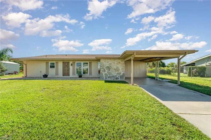 View of front of home with a carport, stone siding, and concrete driveway
