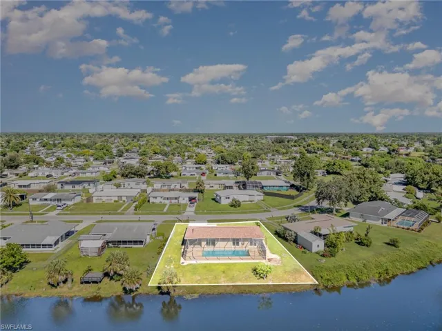 Aerial view of residential area with property boundaries highlighted and a nearby body of water