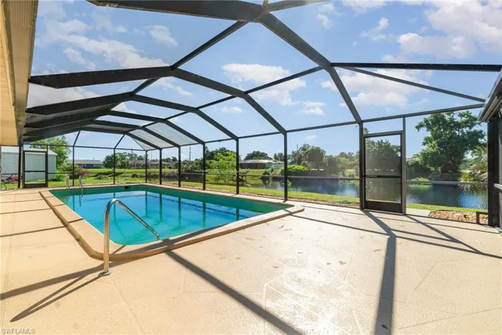Outdoor pool with a sunroom, glass enclosure, a patio, and a water view
