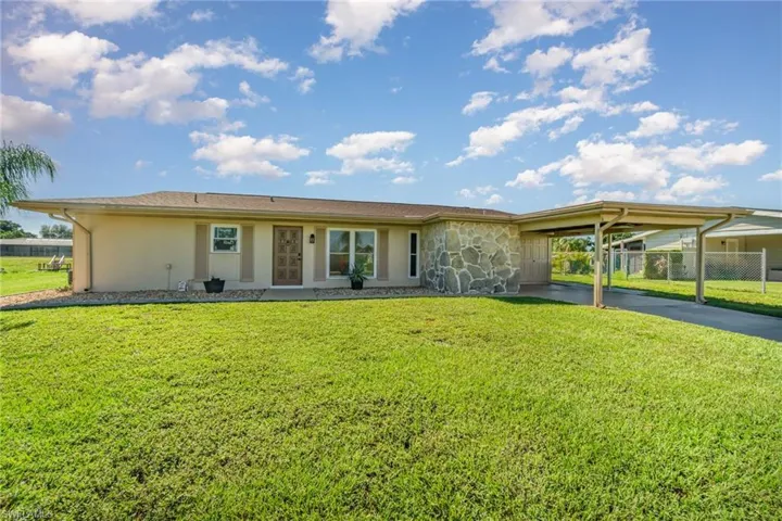View of front of property with concrete driveway, a carport, stone siding, and stucco siding