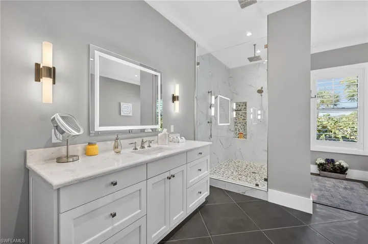 Primary Bathroom featuring vanity, a marble finish shower, dark tile patterned floors, recessed lighting, and crown molding