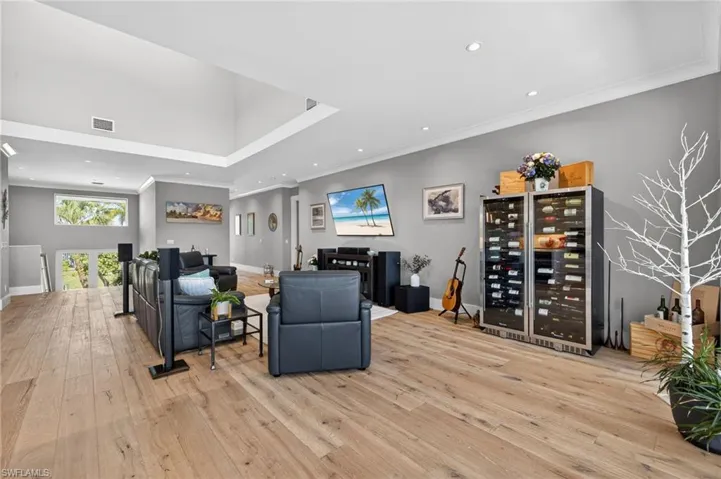 Living room with wine cooler, recessed lighting, light wood-type flooring, and ornamental molding