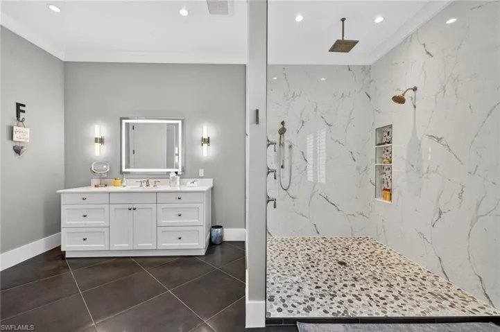 Primary Bathroom with vanity, a marble finish shower, ornamental molding, recessed lighting, and dark tile patterned flooring