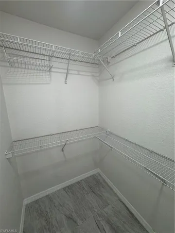 Walk-in closet featuring built-in wire shelving, integrated hanging rods, and wood-finish flooring