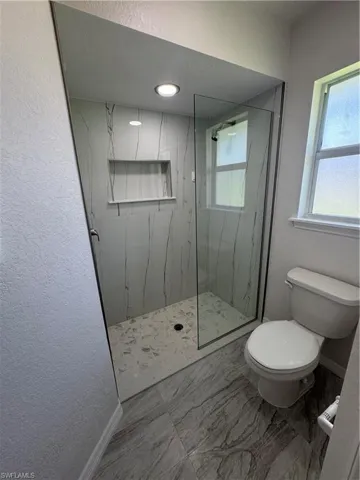 Primary bath with a walk-in shower and glass enclosure, a built-in shower niche, and recessed lighting