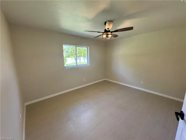 Second bedroom with neutral wall tones, large format tile flooring
