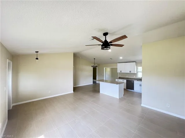 Open-concept main living area featuring tile flooring, a modern ceiling fan, recessed lighting, and a kitchen island with stone countertops