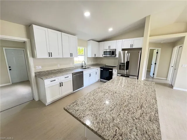 Kitchen featuring a spacious island, granite countertops, white soft close cabinets, stainless steel appliances, and tile flooring