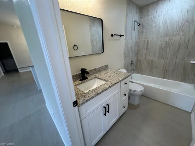 Guest Bathroom with a white vanity, granite countertop, a matte black faucet, and a rectangular mirror