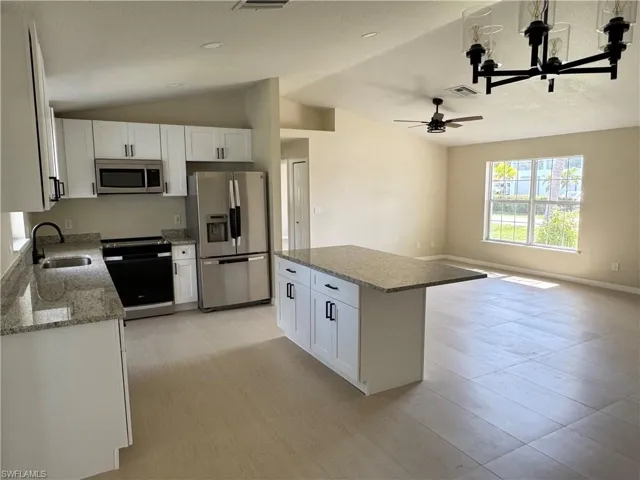 Open-concept kitchen featuring new cabinets, granite countertops, stainless steel appliances, and island with bar seating