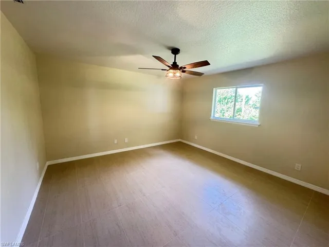 Spacious room featuring tile flooring, a large window, and light-toned walls