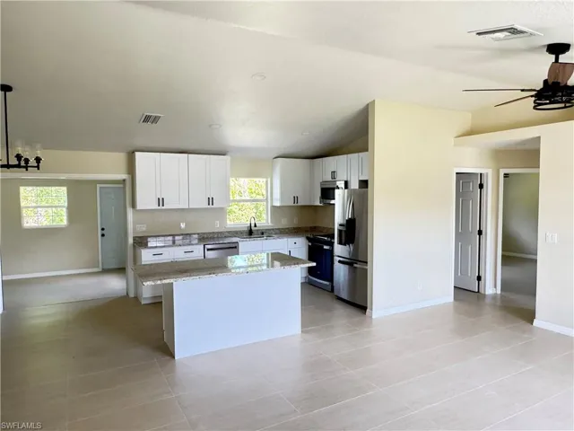 Open-concept kitchen featuring soft close cabinets, granite countertops, stainless steel appliances, a center island, and tile flooring