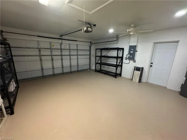 Spacious garage featuring finished floor, overhead lighting, a ceiling fan, and a service door