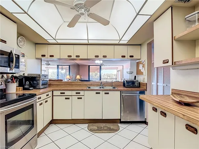Kitchen with stainless steel appliances, white cabinetry, open shelves, and plenty of natural light
