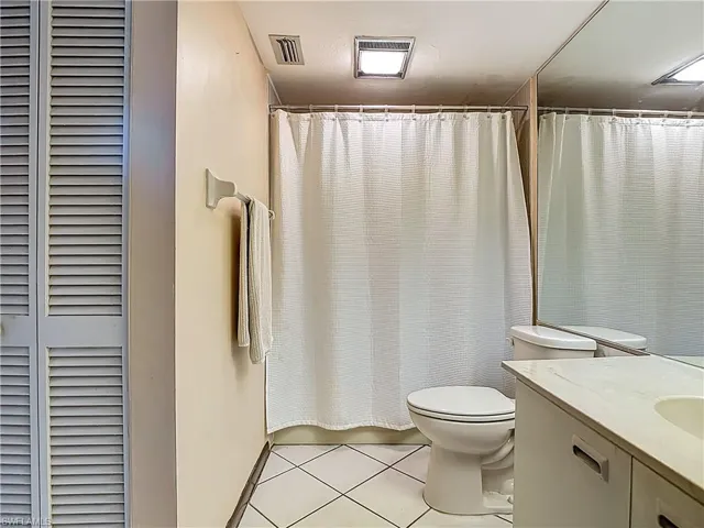 Bathroom featuring vanity, a shower with curtain, light tile patterned floors, and a closet