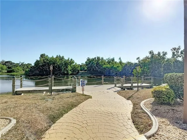 View of community featuring a water view, a dock, and view of scattered trees