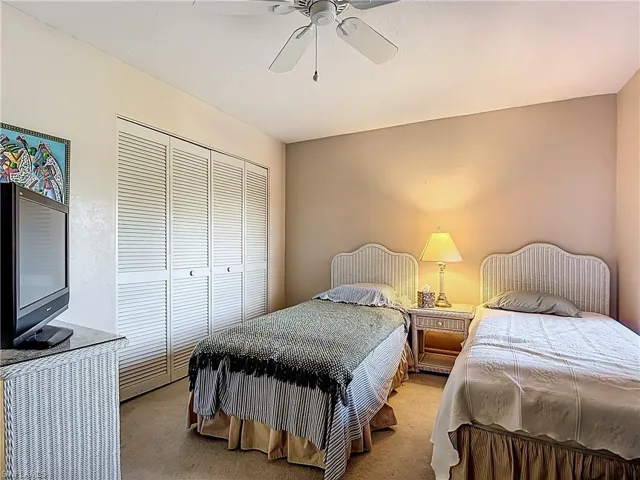 Carpeted bedroom featuring a closet and a ceiling fan