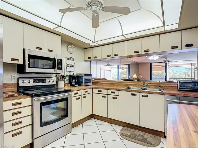 Kitchen with stainless steel appliances, a ceiling fan, and white cabinetry