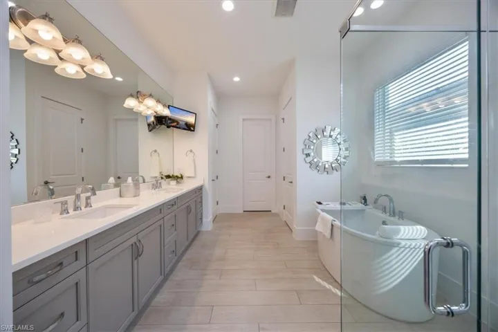 Luxurious primary bathroom with  frameless glass shower and bathtub