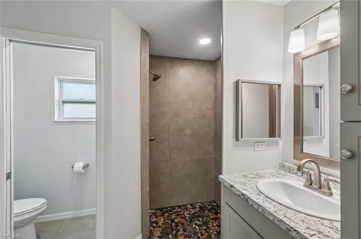 Bathroom featuring a walk-in shower with pebble flooring and large format wall tile