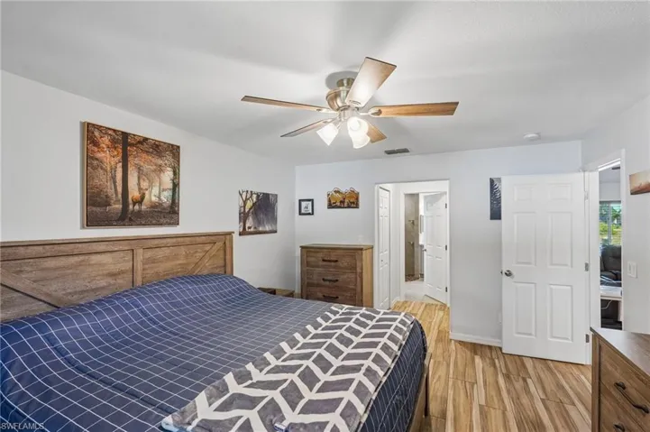 Spacious room featuring wood-finish flooring, a ceiling fan with light fixture, and light-toned walls