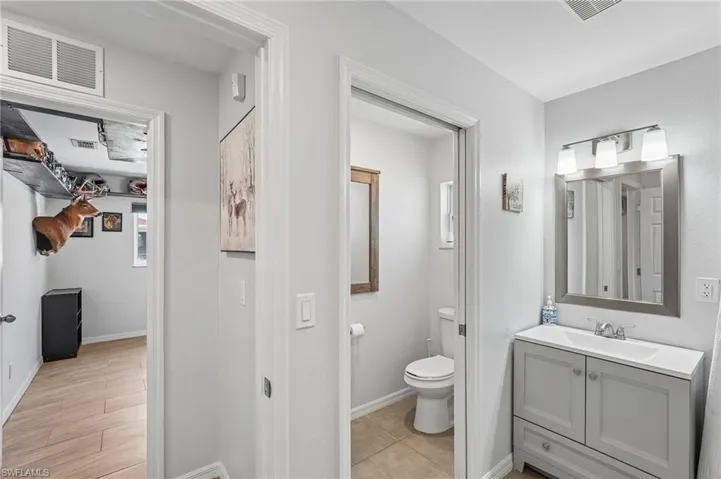 Bathroom featuring a gray vanity with an integrated sink, a framed wall mirror, and a three-light fixture