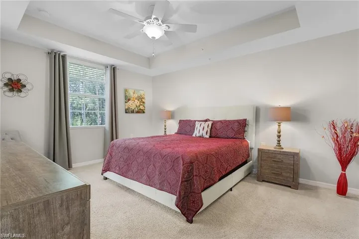 Bedroom featuring a tray ceiling, ceiling fan, and light carpet