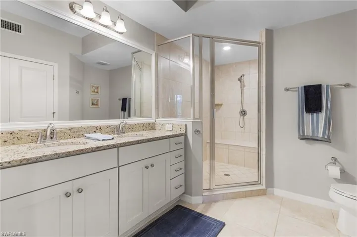 Bathroom with tile patterned flooring, vanity, toilet, and an enclosed shower
