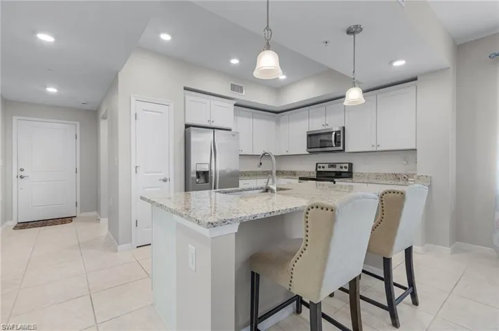 Kitchen featuring white cabinets, sink, stainless steel appliances, and an island with sink