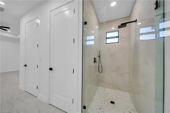 Full bathroom with a marble finish shower, recessed lighting, and light marble finish floors