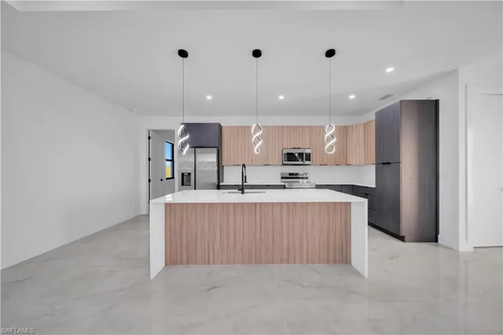 Kitchen featuring a kitchen island with sink, hanging light fixtures, modern cabinets, recessed lighting, and light stone counters