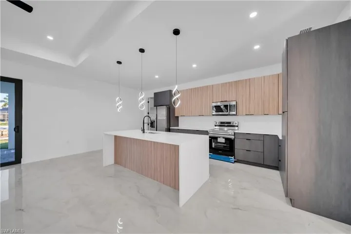Kitchen featuring modern cabinets, stainless steel appliances, light stone countertops, pendant lighting, and light marble finish floors