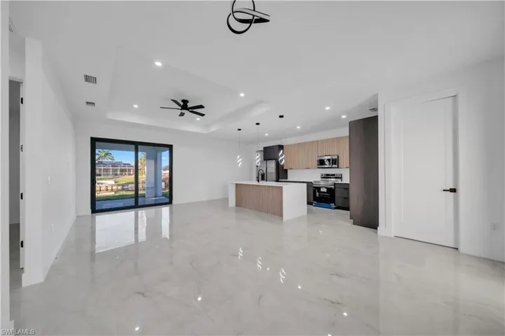 Unfurnished living room featuring light marble finish floors, recessed lighting, a tray ceiling, and ceiling fan