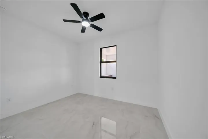 Spare room with light marble finish flooring and a ceiling fan