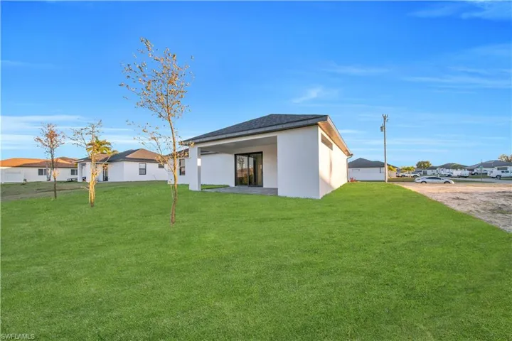 Back of house featuring a patio area, stucco siding, a residential view, and a yard