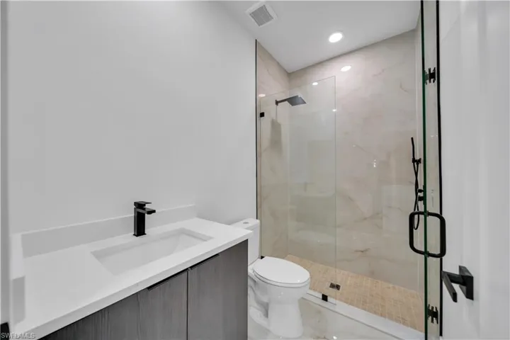 Full bath with vanity, a marble finish shower, recessed lighting, and marble finish flooring