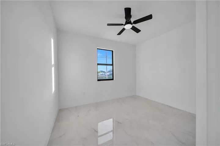 Unfurnished room with light marble finish floors and ceiling fan