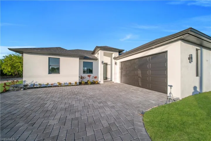 View of front of property featuring stucco siding, decorative driveway, and a garage