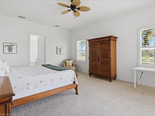 Bright interior space featuring a ceiling fan, white walls, and light-toned carpet flooring