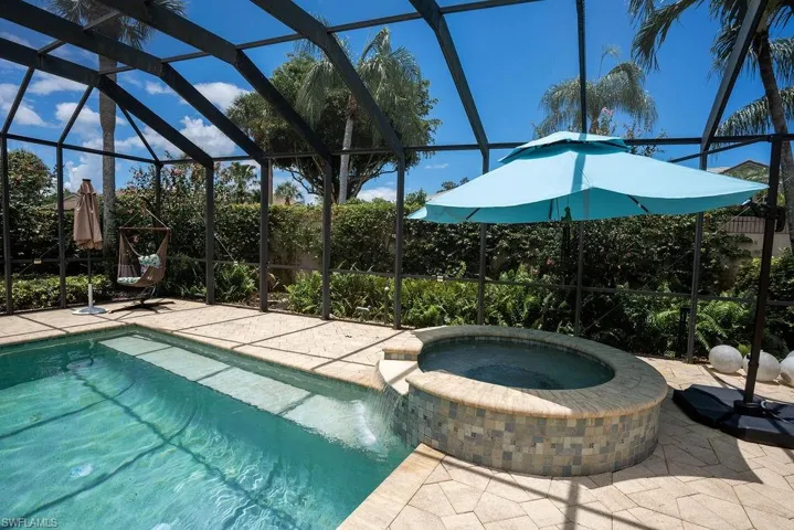 View of pool with a patio, glass enclosure, and an in ground hot tub