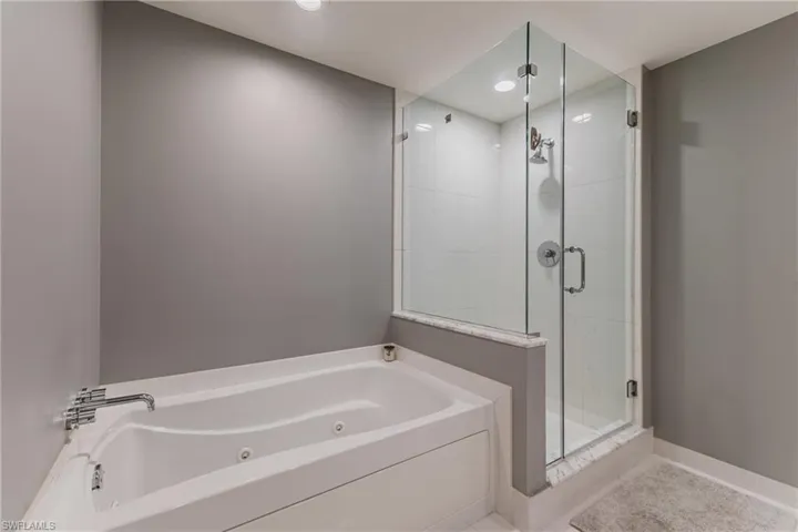 Full bath featuring a shower stall, a jetted tub, and recessed lighting
