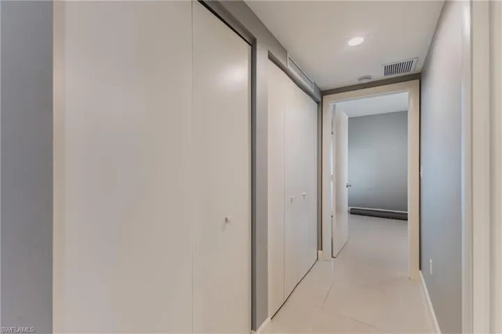 Hall with light tile patterned floors and recessed lighting