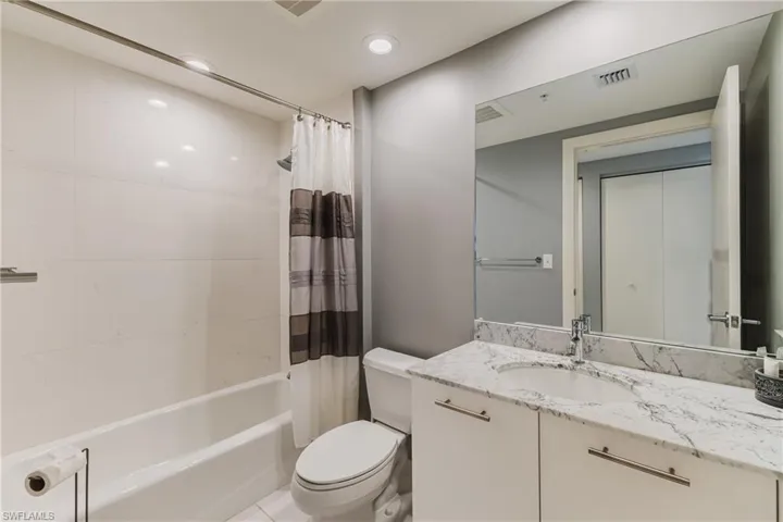 Bathroom featuring vanity, shower / tub combo with curtain, and recessed lighting