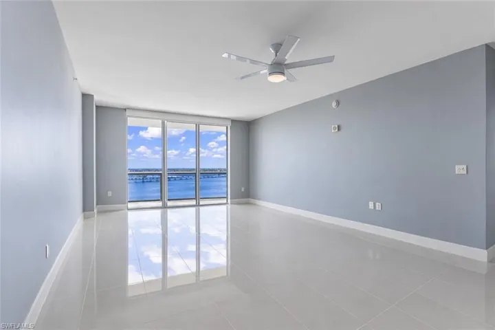 Unfurnished room featuring expansive windows, a ceiling fan, a water view, and light tile patterned flooring