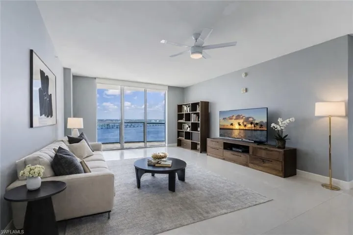Living area virtually staged featuring floor to ceiling windows, a ceiling fan, and light tile patterned floors